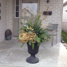 a black vase filled with flowers sitting on top of a porch