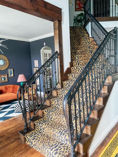 a leopard print carpeted stair case next to a blue wall and wooden handrail