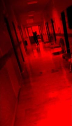 an empty hallway with red light coming from the ceiling