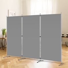 a room divider in front of a white wall with two gray screens on it