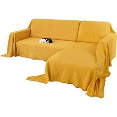 a couch with a dog laying on it next to a blanket that is covering the sofa