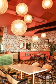 a restaurant with tables, chairs and lamps hanging from the ceiling above them is decorated in black and white checkered tiles