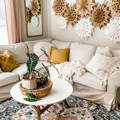 a living room filled with white furniture and lots of decorations on the wall above it