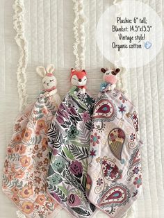 three little stuffed animals hanging from the side of a bed next to some white lace