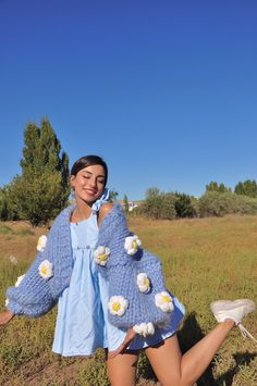 a woman in short shorts and a blue sweater is posing for the camera with her hands on her hips