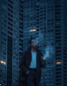 a man standing in front of tall buildings at night