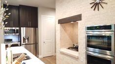 a modern kitchen with stainless steel appliances and white brick walls