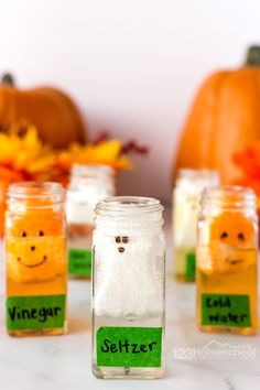 small jars filled with salt sitting on top of a table next to pumpkins and leaves