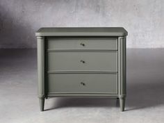 a grey chest of drawers sitting on top of a white floor next to a gray wall