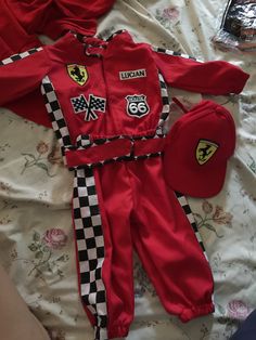 a red racing suit and hat laying on top of a bed