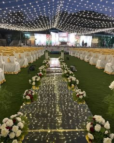 an outdoor wedding venue set up with white and yellow flowers on the grass, surrounded by string lights