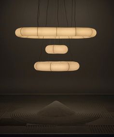 three suspended lights in the middle of a room with black walls and flooring on either side