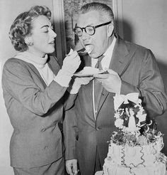 an old man and woman feeding each other cake