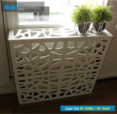 a white radiator in front of a window with potted plants on it