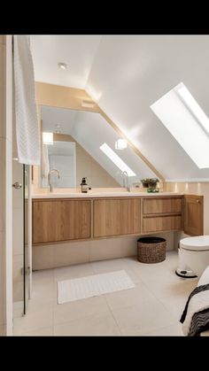 an attic bathroom with skylights above the sink and toilet, along with a rug on the floor