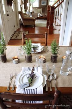 the table is set with place settings for two people to sit down and have plants in them