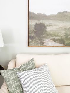 a living room with a white couch and painting on the wall