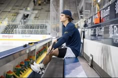 a man sitting on top of a bench next to an ice hockey rink filled with yellow and green cups