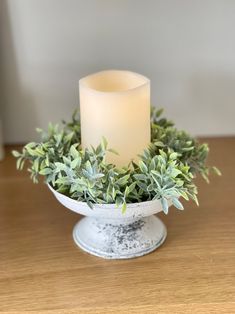 a lit candle sitting on top of a bowl filled with greenery