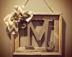 a wooden sign hanging on the wall with a flower and ribbon attached to it's letter