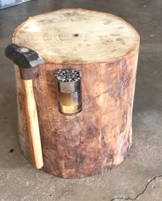 an old tree stump with a hammer and nut in it's center, sitting on concrete