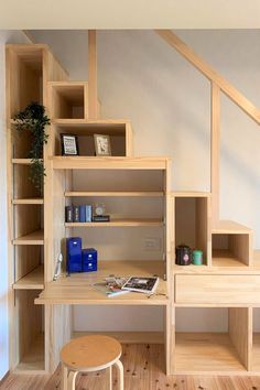 a wooden desk sitting under a stair case next to a wall mounted shelf with books on it