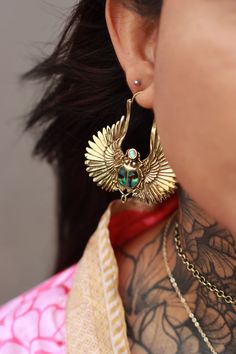 a close up of a person with tattoos on their neck and wearing large gold earrings