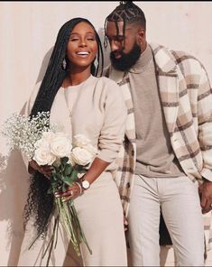 a man and woman standing next to each other with flowers in front of their faces