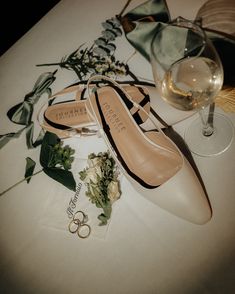 a pair of shoes sitting on top of a table next to a glass of wine