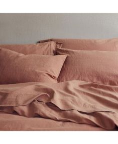 an unmade bed with pink sheets and pillows