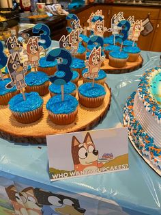 cupcakes with blue frosting and cartoon characters are on display at a children's birthday party