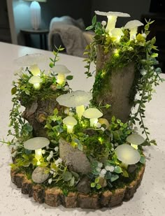 a table topped with a tree stump covered in flowers and plants next to a candle holder