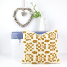 a crocheted pillow sitting on top of a table next to a white vase