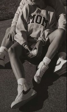 a young man sitting on the ground wearing sneakers