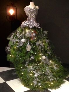 a christmas tree with lights and decorations on it's top is in the middle of a checkered floor