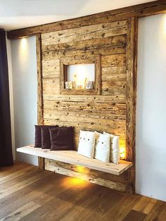 a wooden bench sitting in front of a wall with pillows on it's back