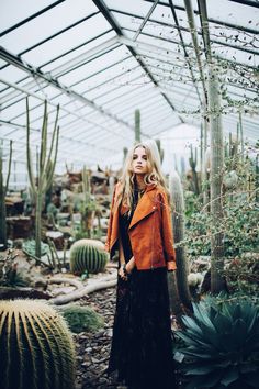 a woman standing in front of cacti and succulents at a greenhouse