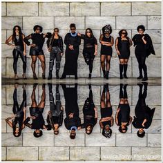 a group of people standing next to each other in front of a wall with mirrors