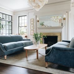 a living room filled with blue couches and a table in front of a fire place