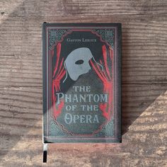 the phantom of the opera book sitting on top of a wooden table