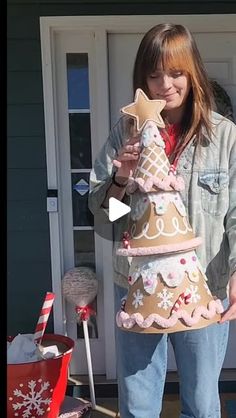 a woman holding up a christmas tree made out of gingerbreads and other decorations