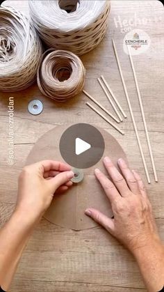 someone is making something out of yarn on a wooden table with scissors and needles in front of them