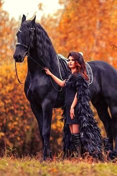 a woman standing next to a black horse