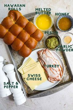 a tray with bread, cheese and meats on it next to other food items