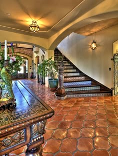 a large foyer with stairs and potted plants on the table in front of it