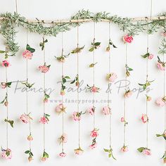 pink flowers and greenery are hanging on the wall