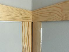 the corner of a wall with some wood on it's side and white walls in the background