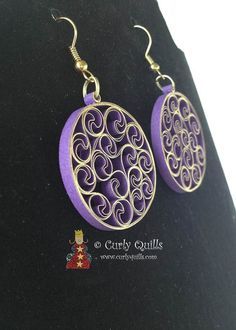 pair of earrings with filigrees in purple and gold tone on black background