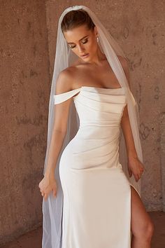 a woman in a white wedding dress with a veil on her head and one leg