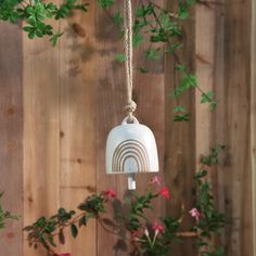 a white bird feeder hanging from a wooden fence